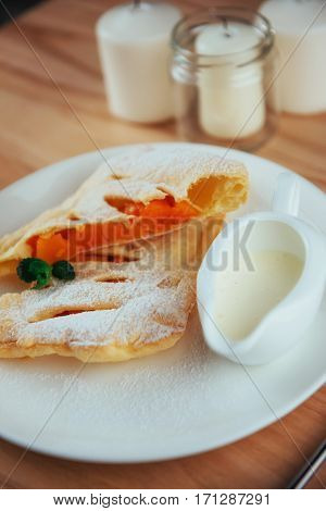 piece of freshly baked pumpkin strudel home with powdered sugar and cream and a sprig of mint