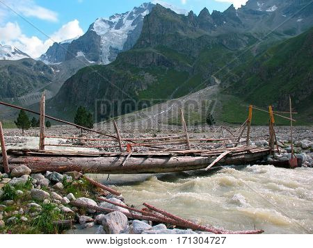 Old wooden bridge over the flashy river in the Caucasus Mountains of Russia.
