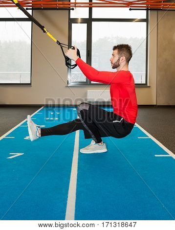 white curly bearded sporty man exercising with fitness straps in gym