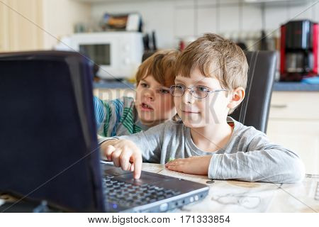 Two little kids boys surfing internet on computer. Children, siblings, friends and twins having fun with learning on pc. Education concept.