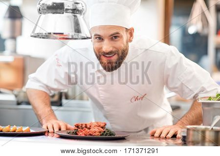 Portrait of chef cook in uniform with prepaired delicious dish at the restaurant kitchen