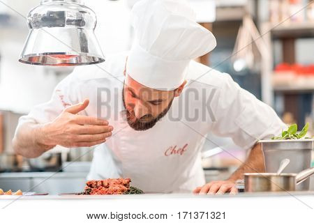 Portrait of chef cook in uniform with prepaired delicious dish at the restaurant kitchen