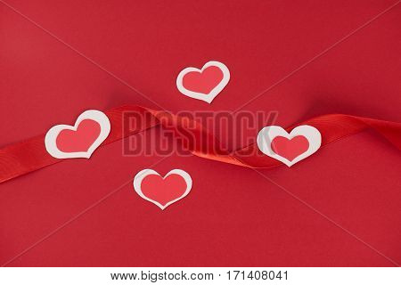 Paper hearts and red ribbon on red background Love card concept Valentine's day theme