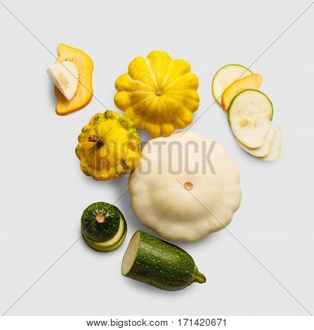 Yellow, white and green zucchini, courgette and round pattipan squashes on white background. Sorts of cucurbit top view