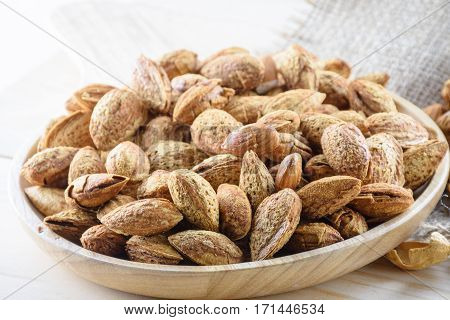 Almond nuts in shell baked with butter and salt on wooden