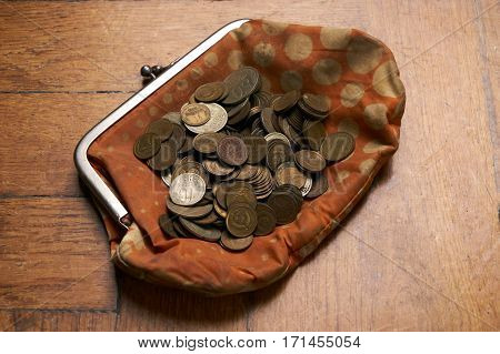 Old retrovintage woman wallet with old collection coins on wooden background.