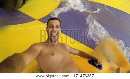 Man having fun and sliding down in a water slide