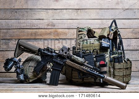 Flak jacket with ammo military equipment assault rifle and helmet on wooden background