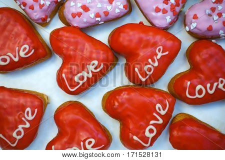 Red and pink donuts with love inscription, top view