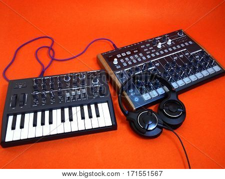 Electronic musical instrument or audio mixer or sound equalizer on a orange background with patch cables and headphones (analog modular synthesizer)