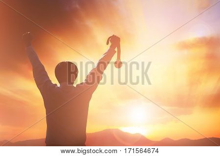 Silhouette business people raising hands and holding gold medal with sunset sky. victory concept.