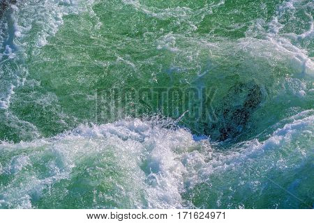 Raging water whirpool among rocks of mountain river in winter