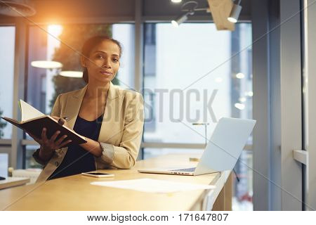 Afroamerican business coach checking report of university student while checking data information from official web site surfing internet using laptop computer connected to free wireless network