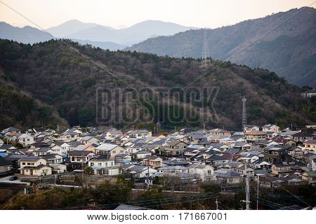 Wide angle view of the suburban houses of Nobeoka Kyushu Japan surrounded by mountains covered in trees. Early spring. Travel and tourism concept.