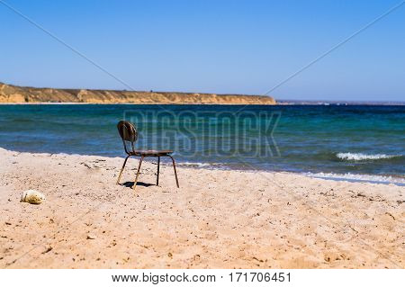 Old chair on the beach. How to select the symbol, loneliness, sadness