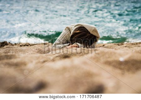 The girl lays on the sand by the sea. He sleeps thinks or enjoying the sound of waves.
