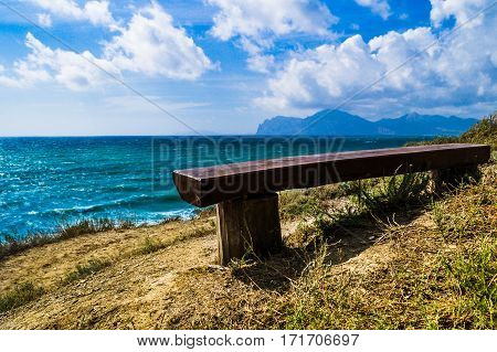 Bench by the sea with mountain views. Like an invitation to stop sit down look around and think.