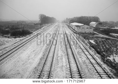 Belarus - November 2016 Long railroad tracks in the snow winter on the railroad farm sheds endless path top view view from the bridge black and white imageroad sign