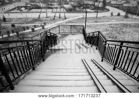Belarus - November 2016 High stairs over the railroad tracks leading into the city the staircase in the snow steps in the snow stairs for baby carriages tracks paths shrubs alley street lights electricity poles