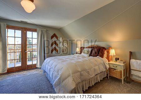 Tranquil Bedroom With Sloped Ceiling And Doors To Nice Deck.