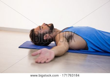 Man in yoga corpse pose in fitness studio
