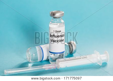 Influenza Flu Vaccine Vials With Syringe Over Turquoise Background