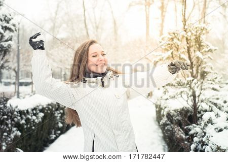 Young beautiful woman play with snow in the park in winter outdoor.