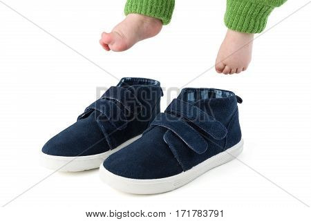 Baby feet with too big blue child shoes isolated on white studio shot