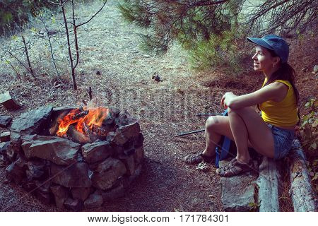 Portrait of happy smiling young woman resting of forest clearing during hike holidays.