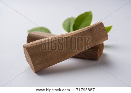 Chandan or sandalwood powder with traditional mortar, sandalwood sticks, perfume or oil and green leaves. selective focus