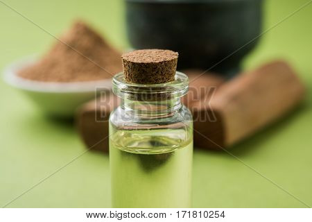 Chandan or sandalwood powder with traditional mortar, sandalwood sticks, perfume or oil and green leaves. selective focus