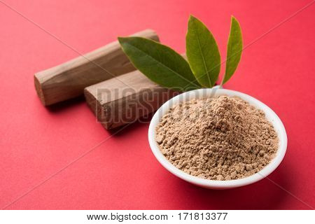Chandan or sandalwood powder with traditional mortar, sandalwood sticks, perfume or oil and green leaves. selective focus