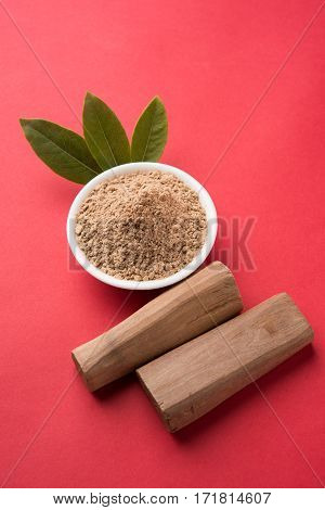Chandan or sandalwood powder with traditional mortar, sandalwood sticks, perfume or oil and green leaves. selective focus