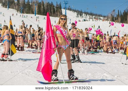 Group Of Young Happy Pretty Women On A Snowboard In Colorful Bikini With Flags.