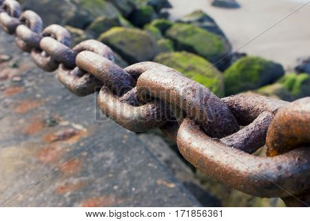 A heavy rusted iron chain by the bay.