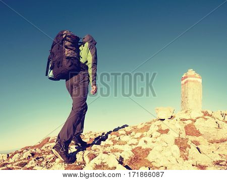 Hiker With Backpack Climbing On Mountain Peak. Summit Stone In Alps