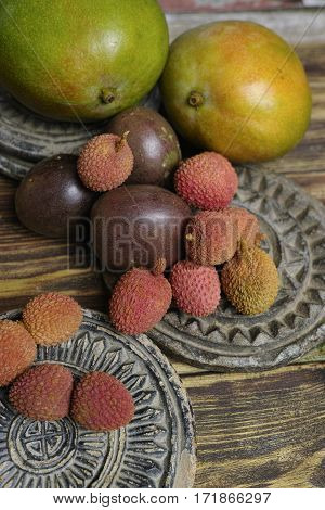Tropical fruits - Lychees and Passion Fruit or Maracuya and Mango on wooden background