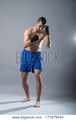 Portrait Of Kickboxer On A Gray Background.