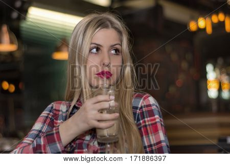 Beautiful young woman holding a cup of coffee . Cheerful female enjoying a cup coffee at cafe.