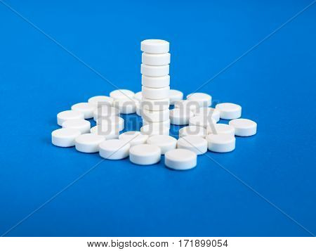 Many white pills on a blue background.