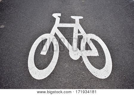 bicycle path stencil of white bike on grey pavement