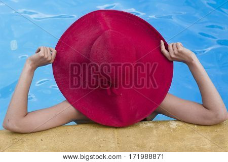 Beautiful blonde woman wearing a hat enjoying the pool summer time
