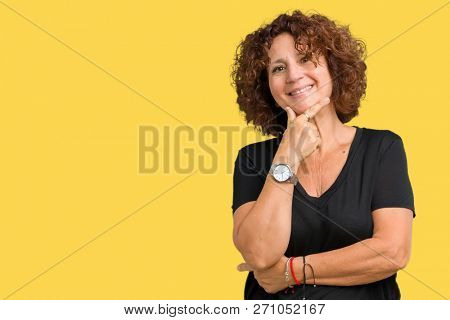 Beautiful middle ager senior woman over isolated background looking confident at the camera with smile with crossed arms and hand raised on chin. Thinking positive.