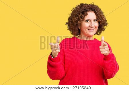Beautiful middle ager senior woman red winter sweater over isolated background pointing fingers to camera with happy and funny face. Good energy and vibes.