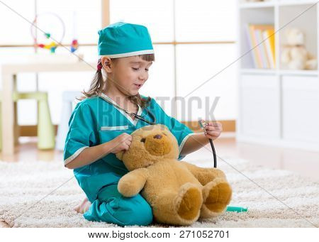 Smiling Kid Girl Playing With Teddy Bear And Pretending She Is A Doctor In Hospital
