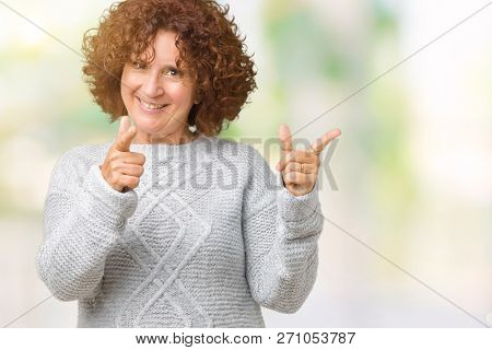 Beautiful middle ager senior woman wearing winter sweater over isolated background pointing fingers to camera with happy and funny face. Good energy and vibes.