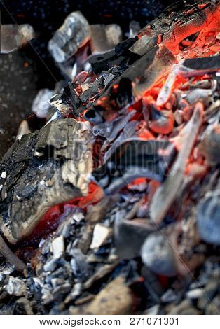 Burning Coals In The Barbecue On A Blurred Background, The Texture Of The Flame