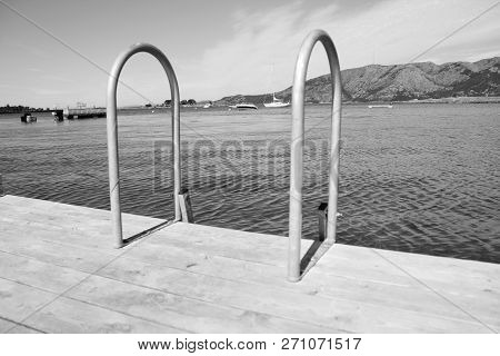 Dock Edge Steel Ladder On Wooden Dock In Black And White.