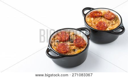Slovak Christmas National Cabbage Soup In Two Small Black Pots With Sausage On The White Background.