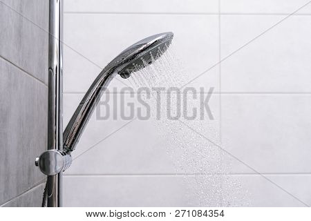 Shower Cabin In A Bathroom. Water Stream Flowing. Silver Shower Head With Running Water In A Bathroo